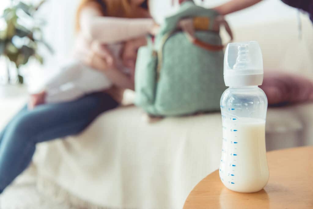 milk in baby bottle with mom and baby in background. How to Sell Breast Milk And Make Extra Money. Are you thinking about selling breast milk? Here are 5 ways to sell breast milk online and in person for babies, bodybuilders, and more.