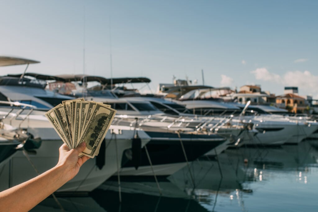 person holding money in front of boats at a marina for a blog post about How to make $5000 fast without a job