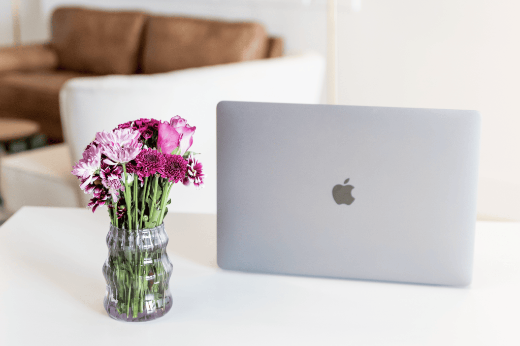 laptop and purple flowers on a desk - How to make money on Fiverr without skills